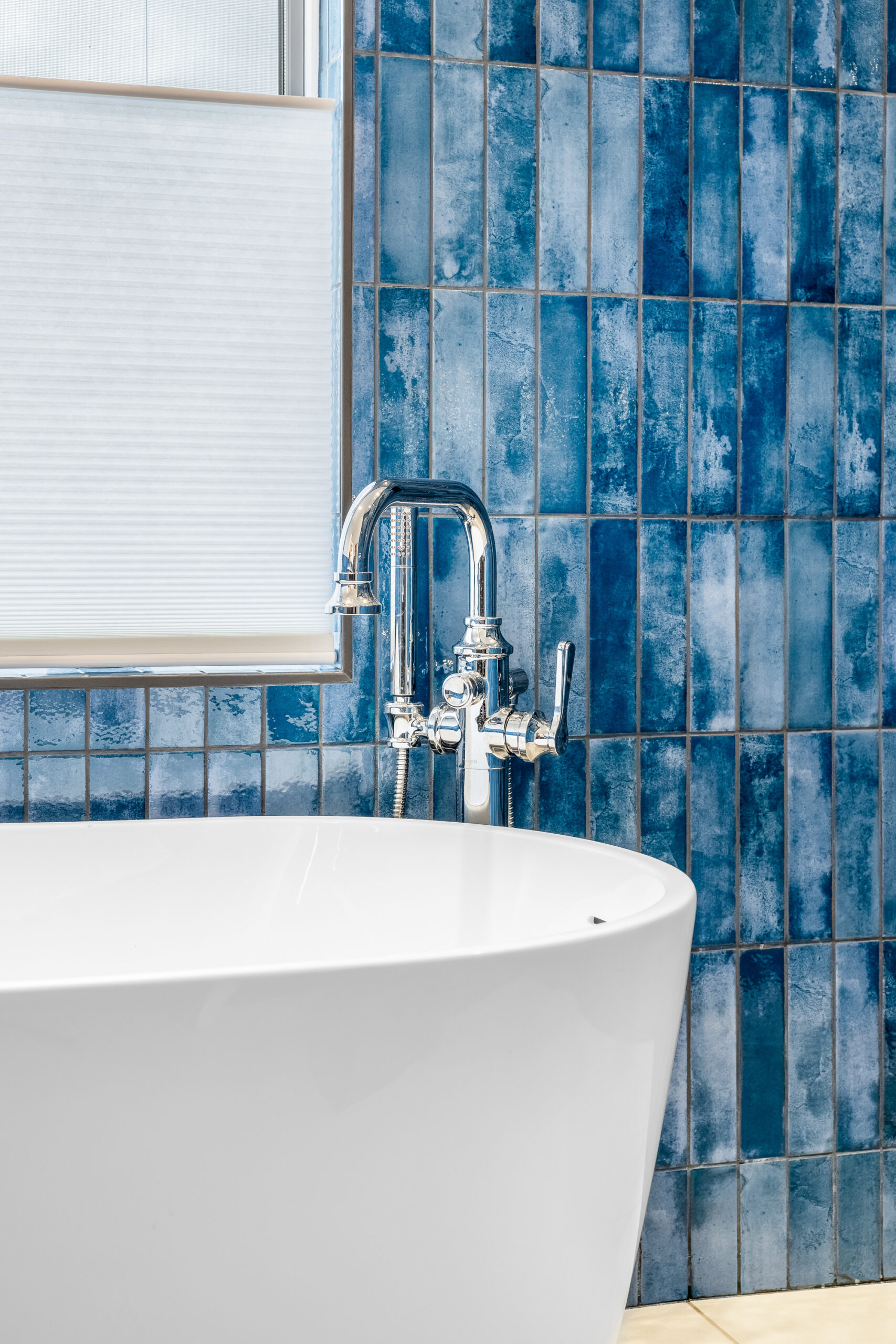 Soaker tub with chrome faucet and blue tile walls