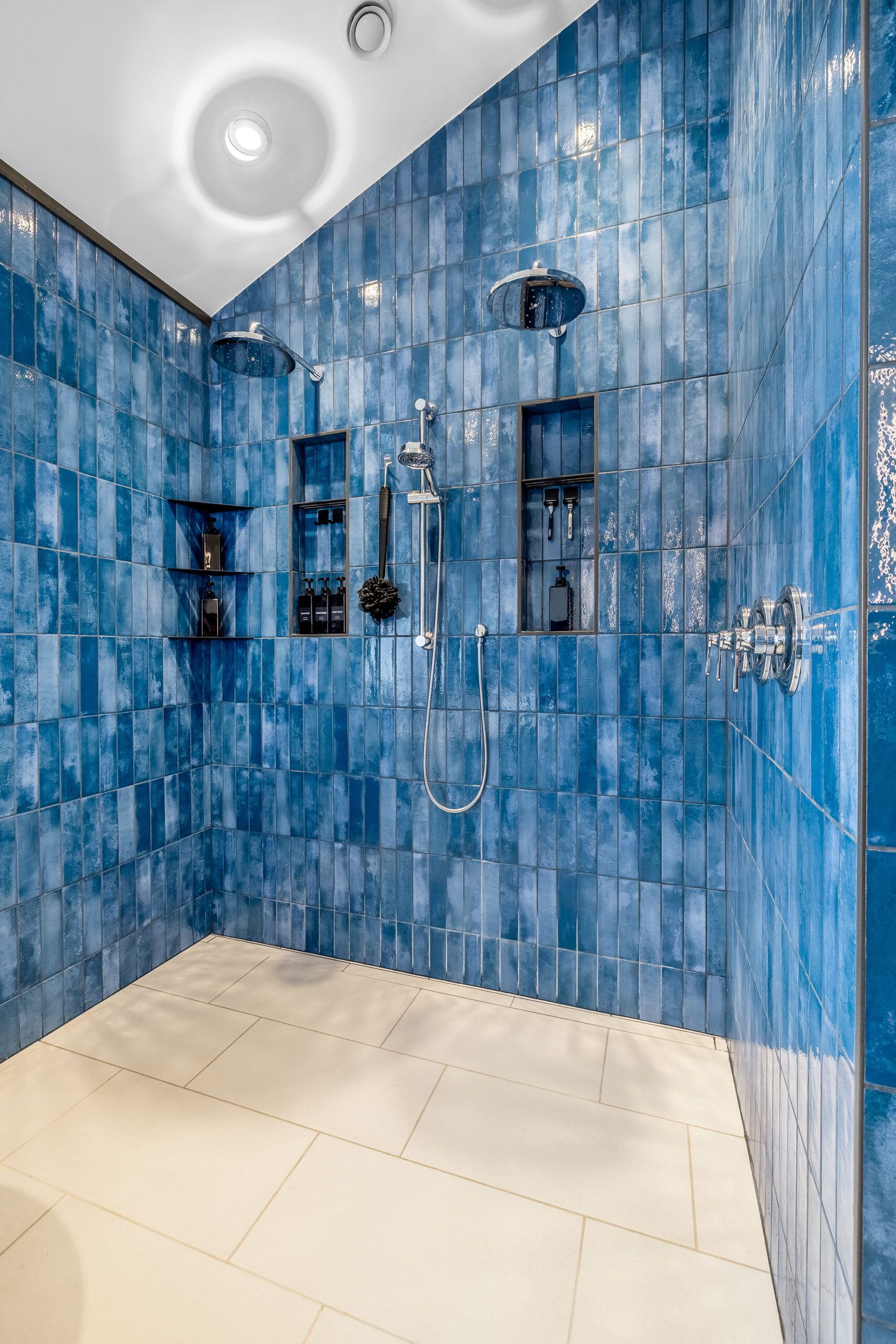 Blue tiled shower with black finishes and large format tiles on floor